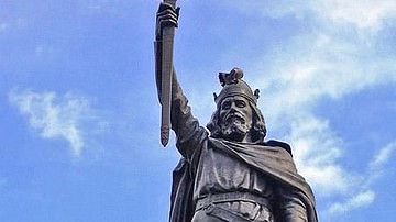Estatua de Alfredo el Grande, alzando su espada, con el cielo de fondo